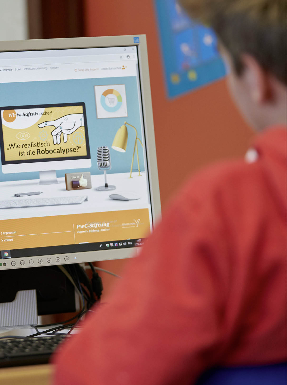 Eine Person in rotem Pullover sitzt vor einem Computerbildschirm, auf dem eine Pr sentation mit dem Titel „Wie realistisch ist die Robocalypse?“ zu sehen ist. Beschreibung von KI generiert